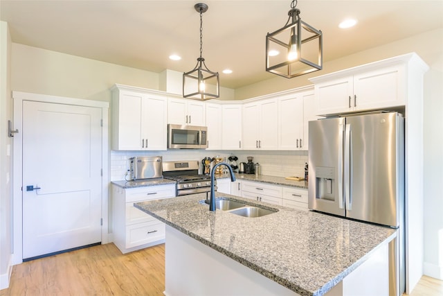 kitchen with a sink, white cabinets, light wood-type flooring, and stainless steel appliances