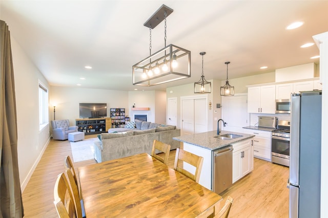 kitchen featuring light wood finished floors, white cabinets, stainless steel appliances, and a sink