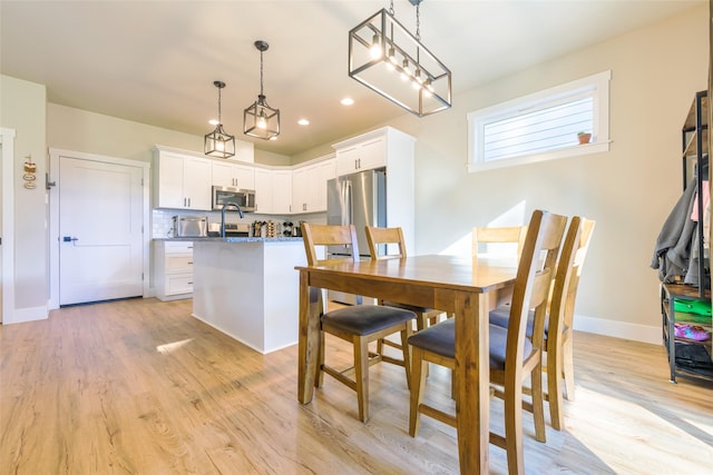 dining room with light wood finished floors, recessed lighting, and baseboards