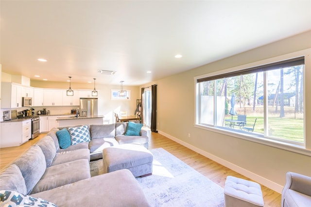 living room with recessed lighting, visible vents, baseboards, and light wood-style floors