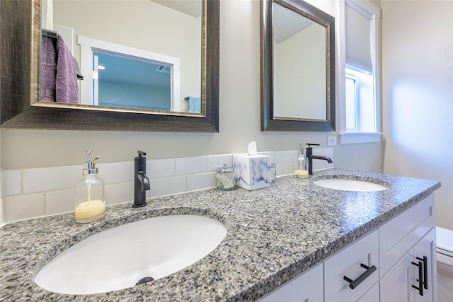 bathroom with a sink, toilet, and double vanity