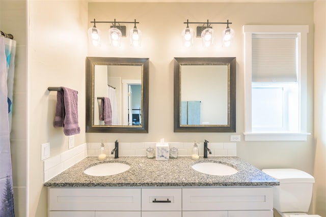 full bath with double vanity, toilet, and a sink