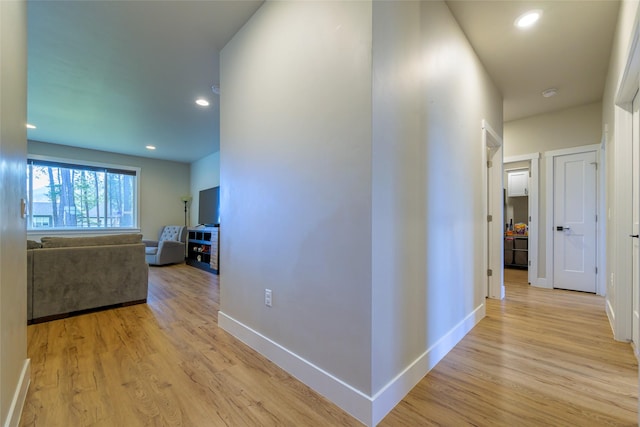 corridor featuring light wood finished floors, recessed lighting, and baseboards