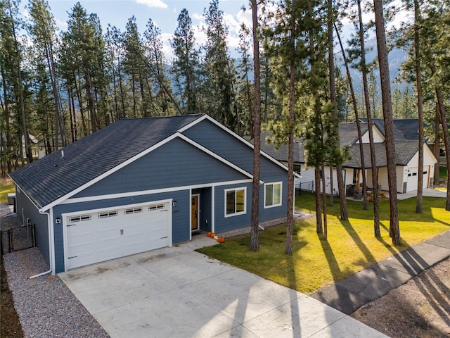 view of front of house featuring a garage, concrete driveway, a front yard, and a shingled roof