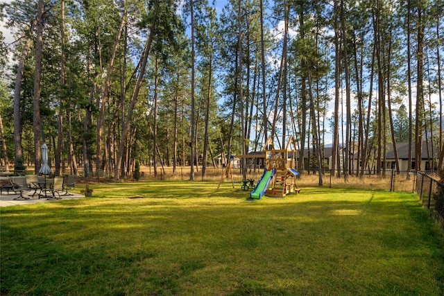 view of yard featuring a patio, a playground, and fence