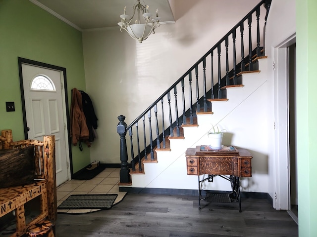 foyer entrance with a notable chandelier, wood finished floors, stairs, and ornamental molding