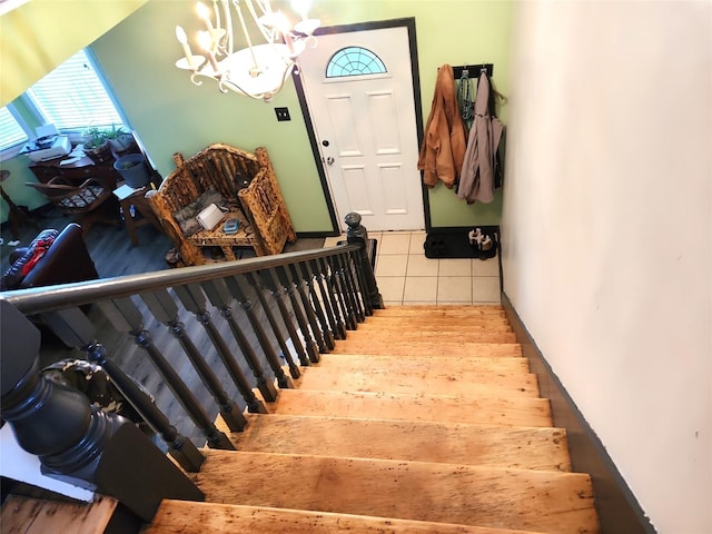 stairs with an inviting chandelier and wood finished floors