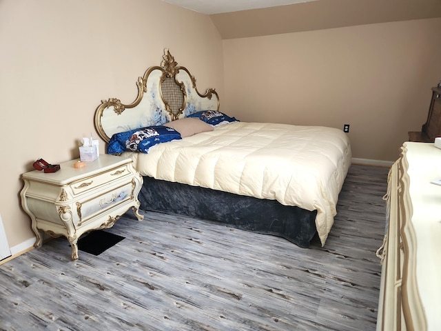 bedroom featuring wood finished floors, baseboards, and vaulted ceiling