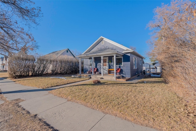 view of front of property featuring a porch, concrete block siding, and a front lawn