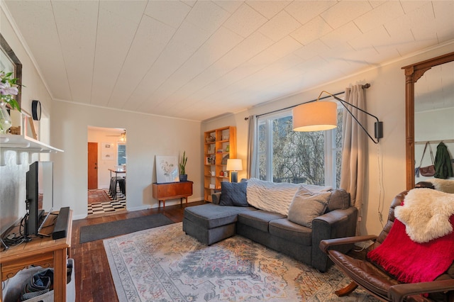 living area with ornamental molding, baseboards, and wood finished floors