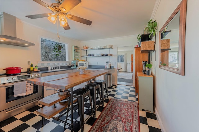 kitchen with white microwave, crown molding, dark floors, stainless steel range oven, and wall chimney exhaust hood