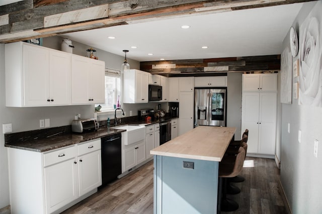 kitchen with black appliances, light wood-style flooring, a breakfast bar, a sink, and white cabinets