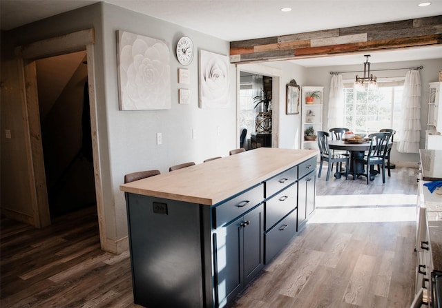 kitchen with decorative light fixtures, a notable chandelier, wood finished floors, and butcher block counters