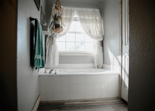 full bathroom featuring a garden tub and wood finished floors