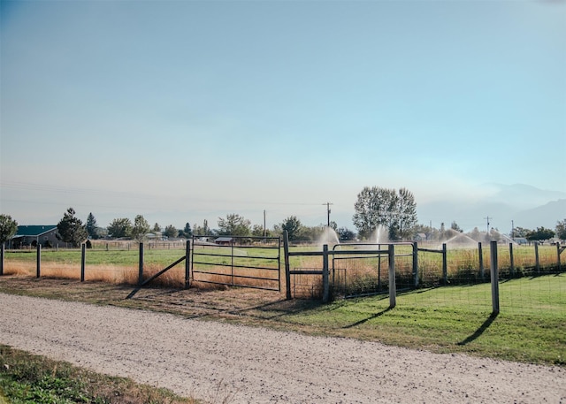 exterior space featuring a rural view, a lawn, and fence