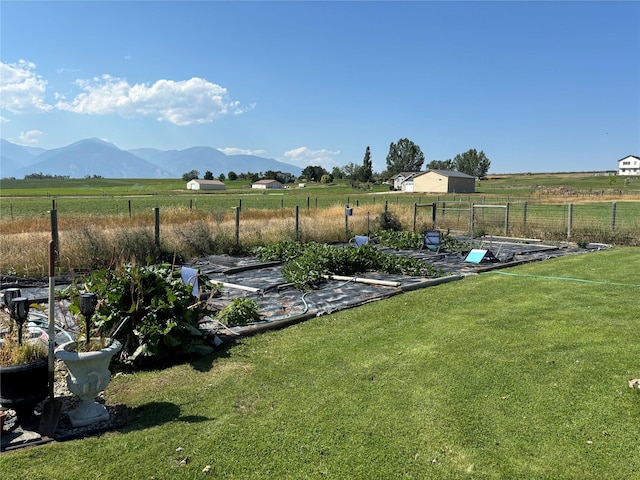 view of yard featuring a mountain view, a rural view, a vegetable garden, and fence