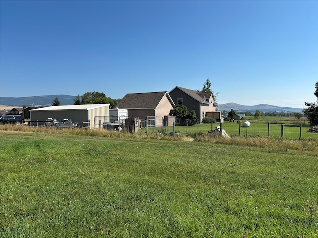 view of yard with an outbuilding, a pole building, a mountain view, and fence