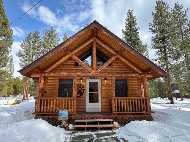 log cabin with log siding and a porch