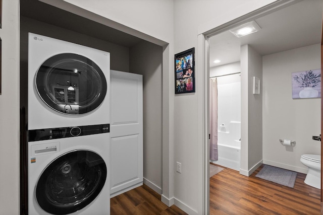 laundry room with baseboards, stacked washer and clothes dryer, dark wood finished floors, and laundry area