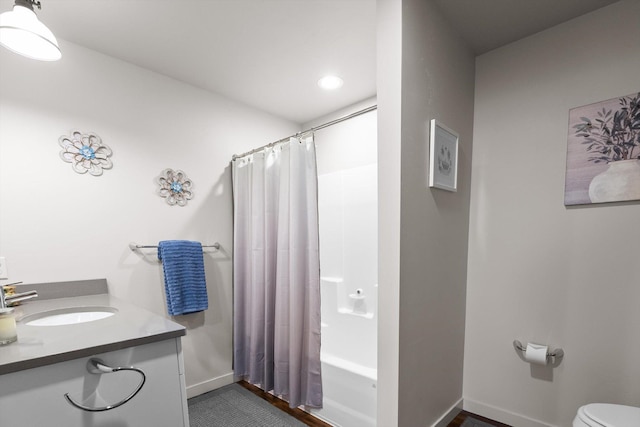 bathroom with toilet, vanity, shower / tub combo, and baseboards