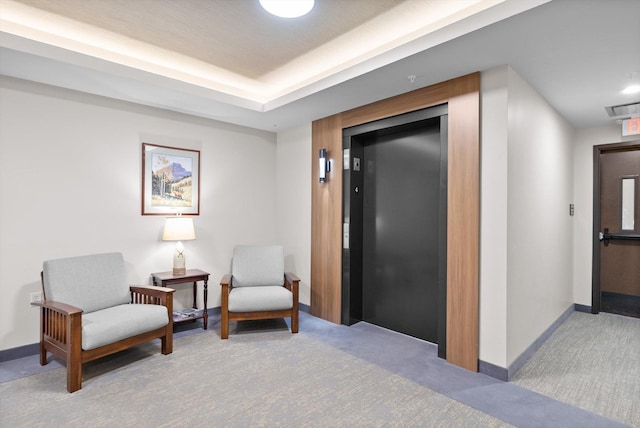 living area with baseboards, visible vents, elevator, and carpet floors