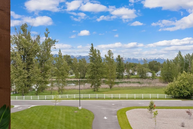 view of property's community featuring a mountain view, a yard, and fence