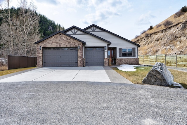 craftsman-style house featuring concrete driveway, an attached garage, fence, and brick siding