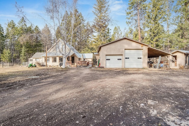 exterior space featuring driveway, a detached garage, an outdoor structure, and fence