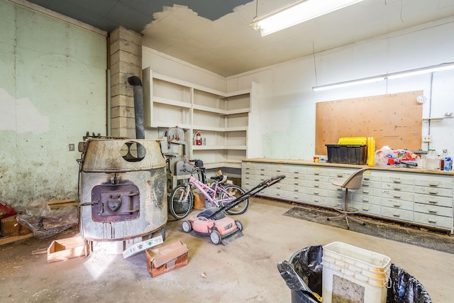 interior space with a workshop area, concrete floors, and a wood stove