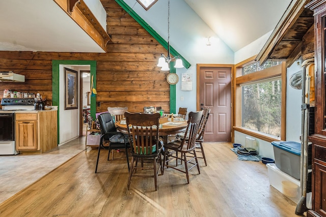 dining room with an inviting chandelier, a skylight, light wood-style floors, and high vaulted ceiling