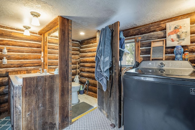 clothes washing area with laundry area, a textured ceiling, washer / clothes dryer, and a sink