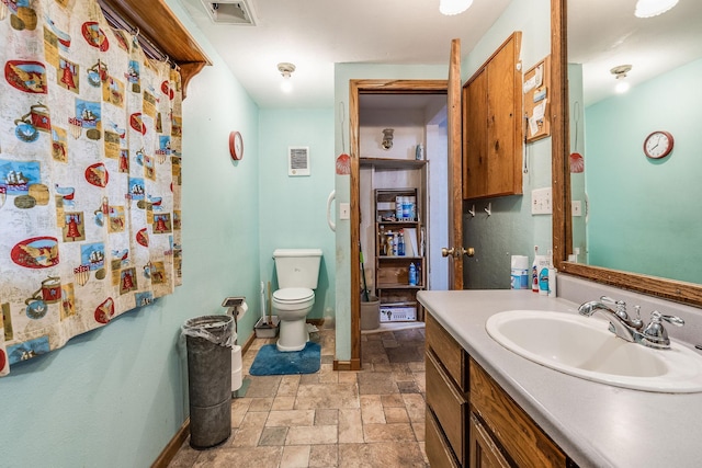 bathroom featuring vanity, stone tile floors, baseboards, visible vents, and toilet