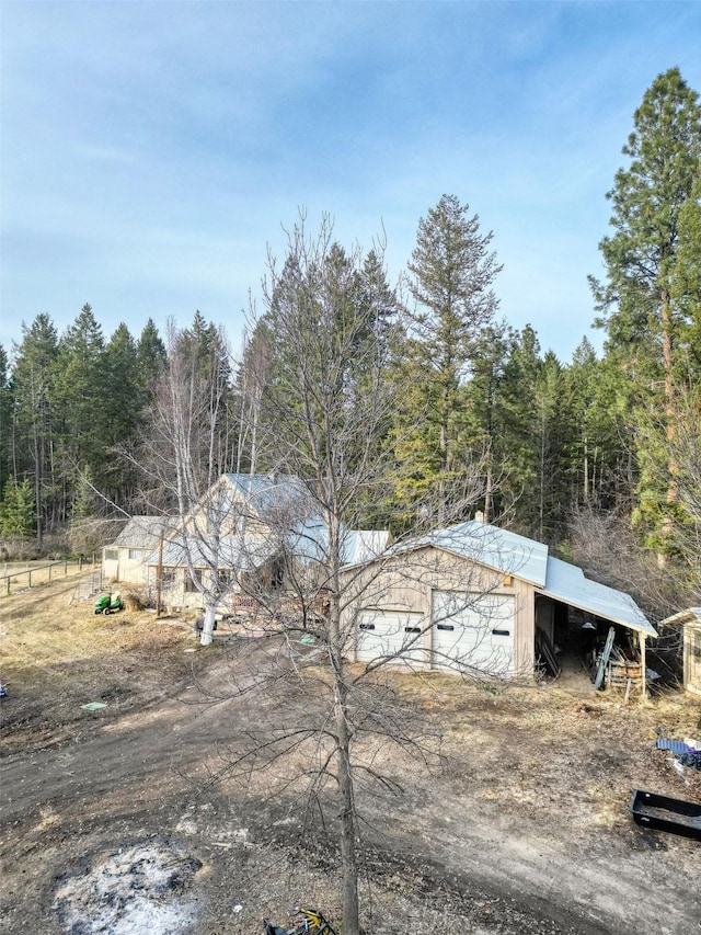 view of yard with a detached garage and a view of trees