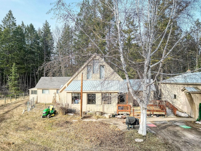 back of property with a standing seam roof, fence, board and batten siding, metal roof, and a wooden deck