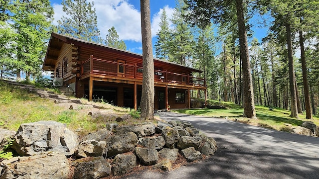 view of front facade with log siding, driveway, and a deck