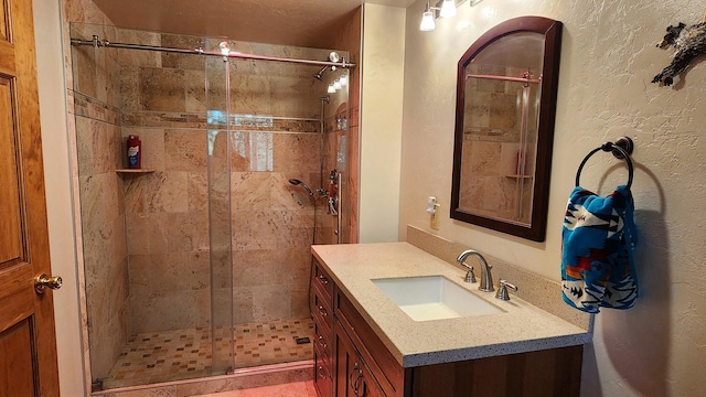 bathroom with vanity, a shower stall, and a textured wall