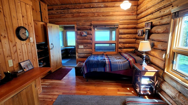 unfurnished bedroom with log walls, wood ceiling, and hardwood / wood-style floors