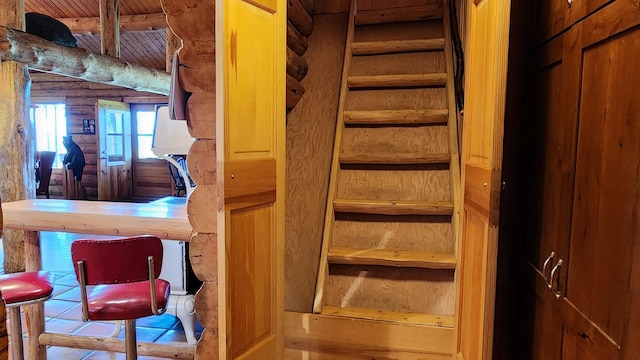 staircase featuring wooden ceiling, beamed ceiling, and log walls