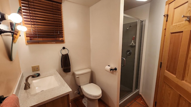 bathroom with vanity, a shower stall, toilet, and baseboards