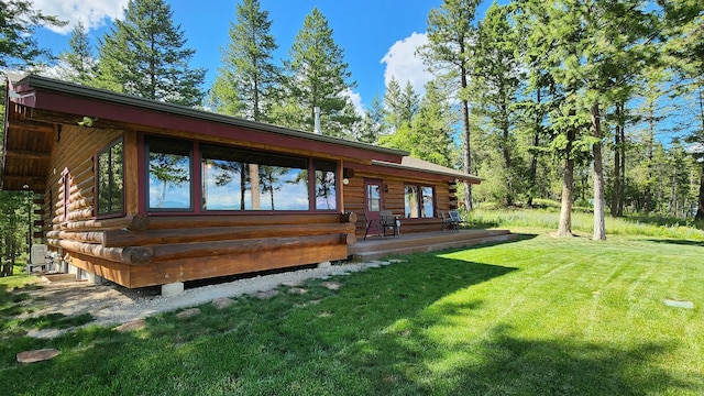 rear view of house with log siding and a lawn