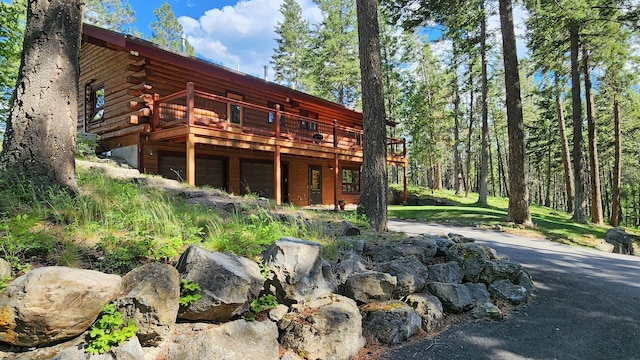 back of house featuring log siding, an attached garage, and a deck