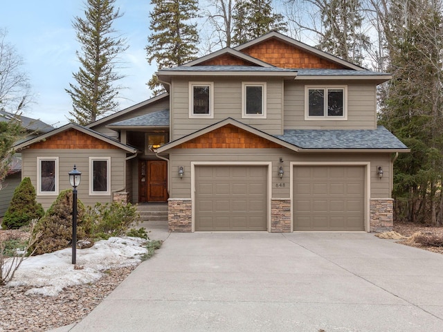 craftsman inspired home featuring a garage, concrete driveway, roof with shingles, and stone siding