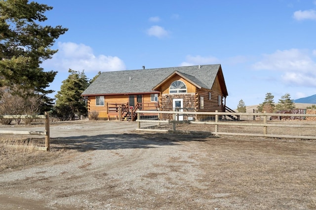 cabin featuring log siding and fence