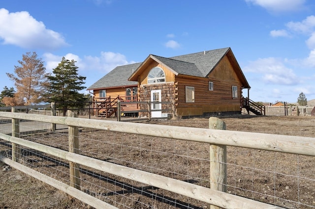 exterior space featuring log exterior, a wooden deck, roof with shingles, and fence