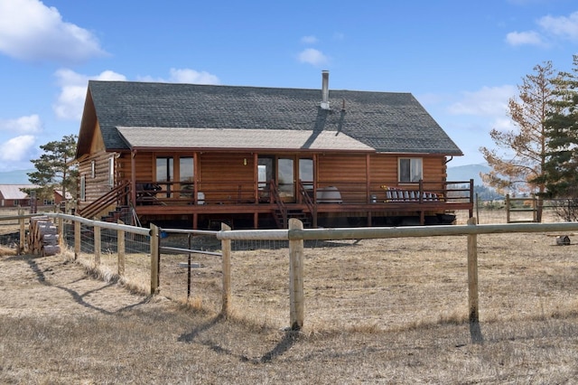 back of property with a deck, log exterior, fence, and a shingled roof