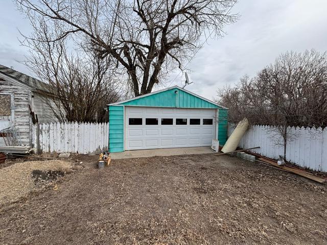 detached garage featuring fence and driveway