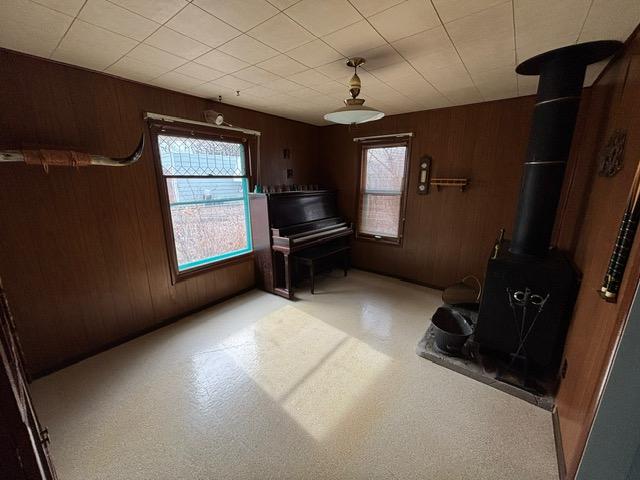 interior space with a wood stove, a healthy amount of sunlight, and wood walls