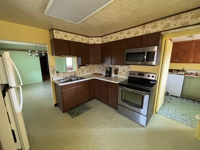 kitchen featuring light floors, light countertops, washer and dryer, stainless steel appliances, and a sink