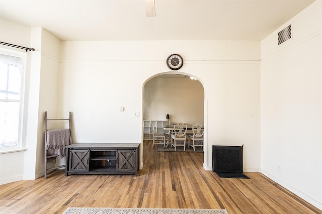 interior space with wood finished floors, arched walkways, and baseboards