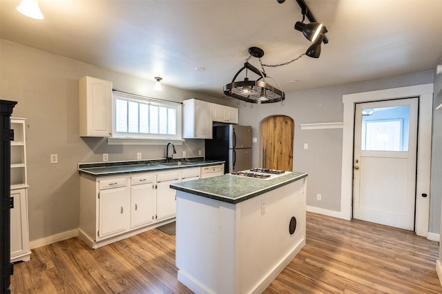 kitchen featuring arched walkways, dark countertops, light wood-style flooring, and freestanding refrigerator